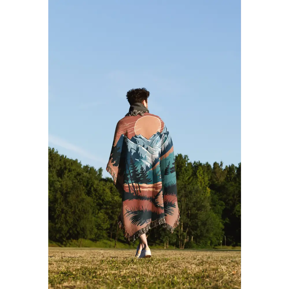 Person wrapped in a mountain-themed Sunset Trail Personalized Woven Blanket